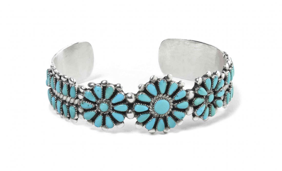 A Zuni Sterling Silver and Turquoise Petit Point Bracel: A Zuni Sterling Silver and Turquoise Petit Point Bracelet, having three circular floral designs flanked by two rows of tear drop shaped stones. Inscribed I. Paylusi. Length 6 1/4 x width 5/8 inches.