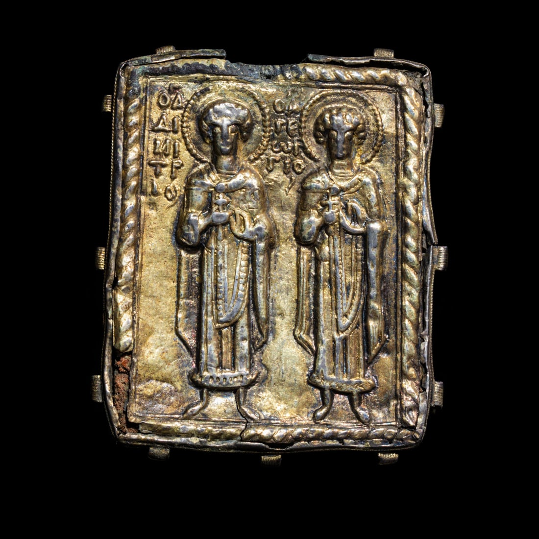 A Byzantine Gilt-Silver Enkolpion with Saints Demetrios and George: A Byzantine Gilt-Silver Enkolpion with Saints Demetrios and George Circa 13th-14th Century A.D. Height 5.5 cm (2 1/8 inches); 22 grams. Provenance: Private Collection (C.M.), Germany, 1970s. Ariadne G
