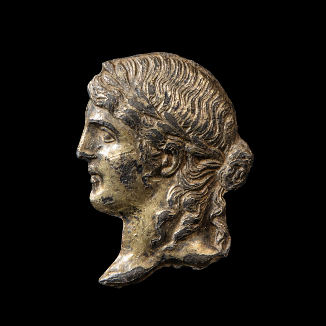 A Greek Gilt-Silver Apollo AppliquÈ: A Greek Gilt-Silver Apollo AppliquÈ Circa Late 4th Century B.C. Height 2.8 cm (1 1/8 inches); 6 grams. Provenance: Private Collection, Germany, 1960s-1970s. Art Market, Europe, 1980s. D. Benaim C