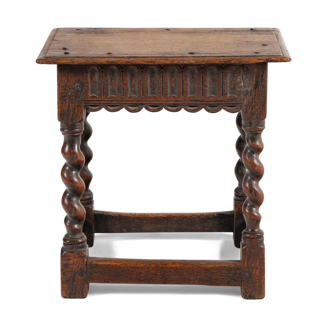 An English Oak Joined Stool: An English Oak Joined Stool 17th Century the carved apron surmounting barleytwist legs joined with a box stretcher. Height 18 x width 18 x depth 11 inches. Property from the Estate of Audrey and Phili