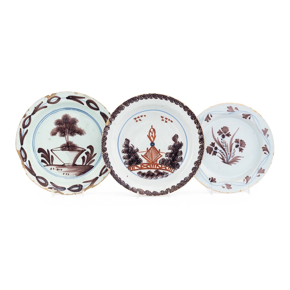 A Collection of Three English Manganese Decorated Delftware Plates: A Collection of Three English Manganese Decorated Delftware Plates 18th Century comprising an example decorated with an iron red Chinoiserie temple withing a garden landscape, an example with a