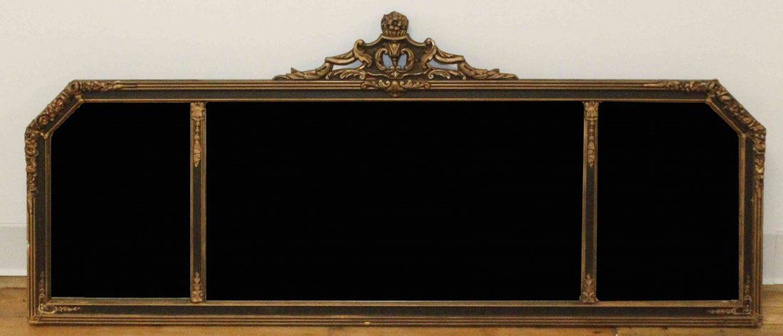 An Ebonized and Parcel Gilt Mirror, Height 21 1/2 x: An Ebonized and Parcel Gilt Mirror, of rectangular form, the top with canted corners, having a carved scrolling crest over three paneled plates. Height 21 1/2 x width 50 inches.