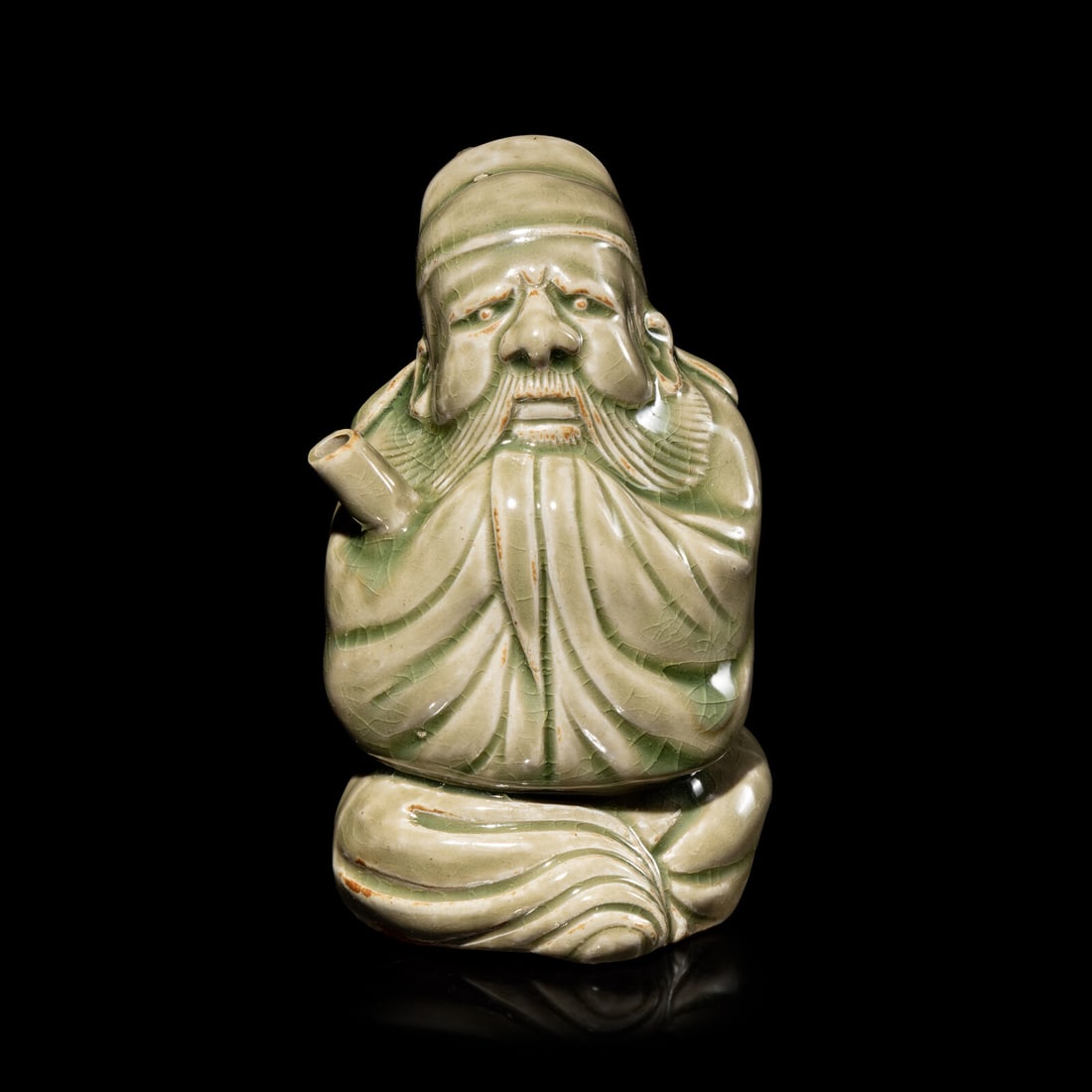 A Chinese Celadon Glazed Porcelain Figure Water Dropper, Yandi: A Chinese Celadon Glazed Porcelain Figure Water Dropper, Yandi 青釉人物形硯滴 Molded in the form of a scholar figure wearing a long robe, holding the spout to