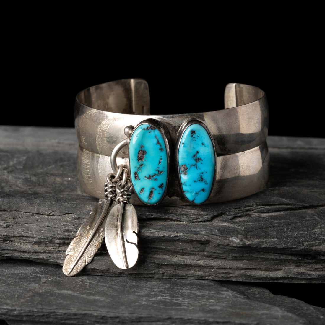 Southwestern-style Sterling Silver and Turquoise Cuff Bracelet: Southwestern-style Sterling Silver and Turquoise Cuff Bracelet third quarter 20th century set with a pair of stones accented with two silver feather pendants; signed illegibly on exterior of