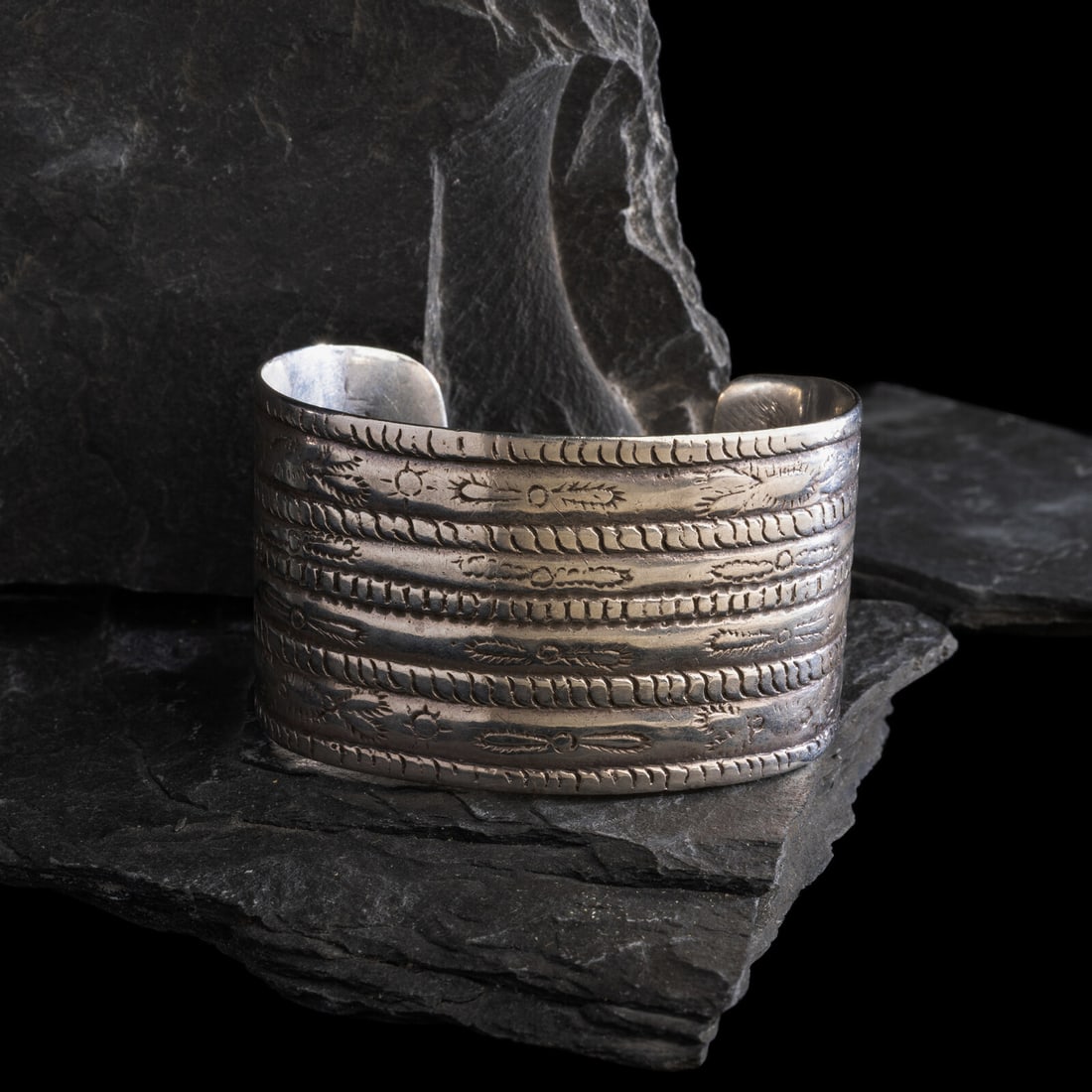 Early Navajo Stamped and Chiseled Ingot Cuff Bracelet: Early Navajo Stamped and Chiseled Ingot Cuff Bracelet ca 1885-1890 heavily worn banded design alternating with bands of chiseled linear elements with bands of suns and bow ties: marked STERLING on int