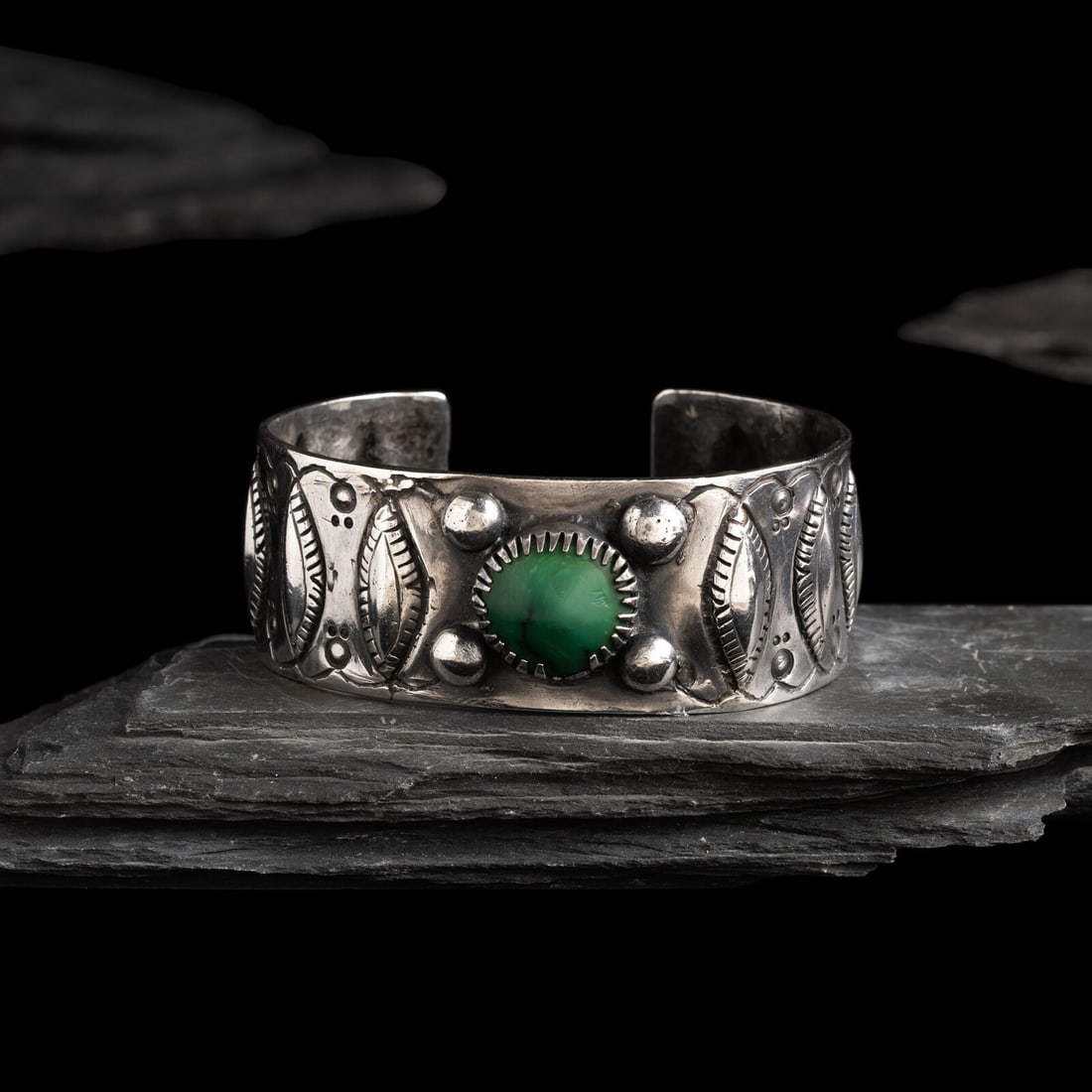 Early Navajo Ingot and Turquoise Cuff Bracelet: Early Navajo Ingot and Turquoise Cuff Bracelet ca 1890 concha design with a row of ten diamond-shaped repoussÈ elements accented with scrolling chiseled design; set with a single stone in a serra