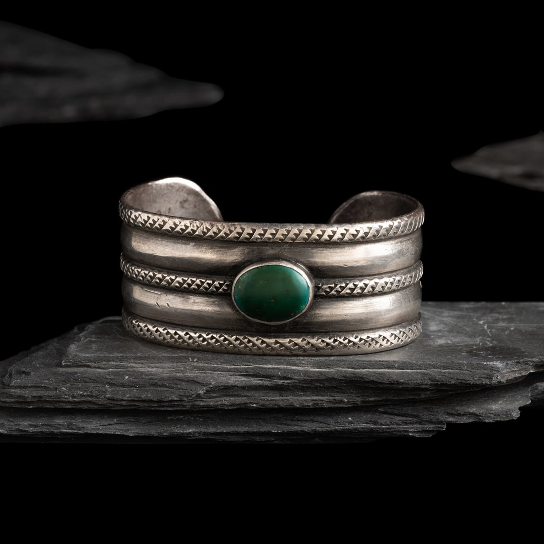 Early Navajo Ingot and Cerillos Turquoise Cuff Bracelet: Early Navajo Ingot and Cerillos Turquoise Cuff Bracelet ca 1890-1910 banded design, featuring alternating stamped bands and chiseled raised bands; set with a single central stone; not marked width 1-1