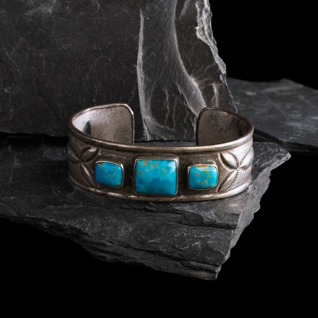 Navajo Ingot and Turquoise Cuff Bracelet: Navajo Ingot and Turquoise Cuff Bracelet first quarter 20th century heavily stamped shank with raised edges, set with three high grade turquoise stones; not marked width 3/4 inch interior circumferenc