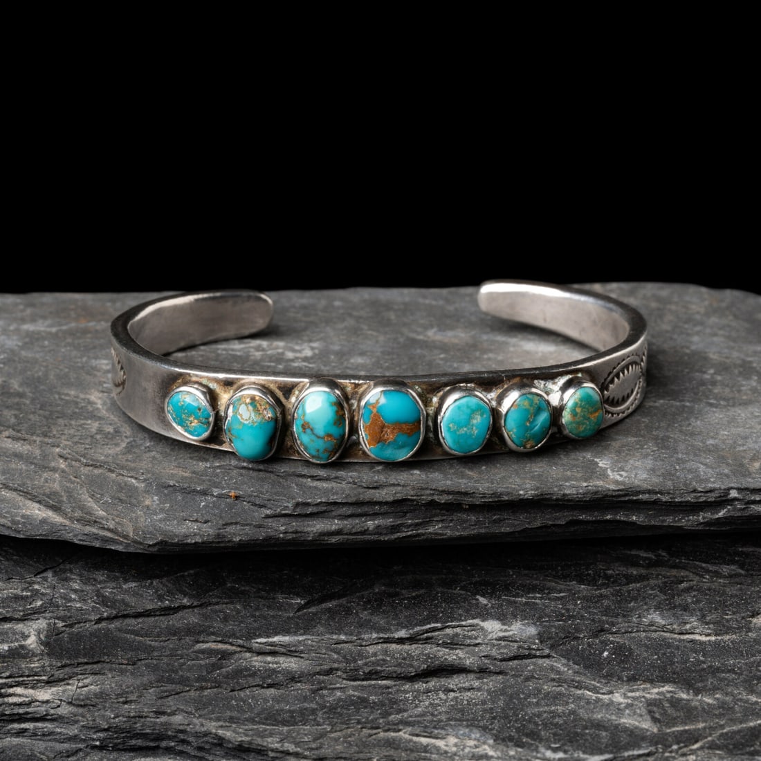 Navajo Silver and Turquoise Cuff Bracelet: Navajo Silver and Turquoise Cuff Bracelet second quarter 20th century set with a row of seven graduated stones and stamping on the shank; not marked width 3/8 inch interior circumference 5-1/8 inches 