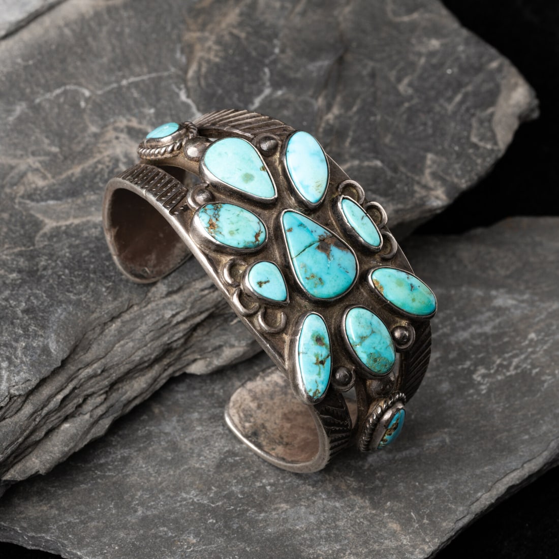 Navajo Turquoise Cluster Cuff Bracelet: Navajo Turquoise Cluster Cuff Bracelet second quarter 20th century split shank cuff with stamped elements and set with 11 stones; not marked width 1-3/8 inches interior circumference 5-1/2 inches +
