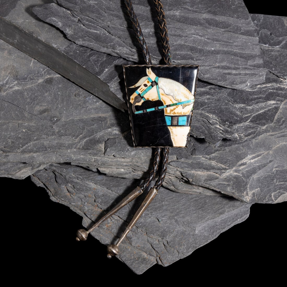 Zuni Mosaic Inlay Equine Bolo Tie: Zuni Mosaic Inlay Equine Bolo Tie mid-20th century trapezoidal-shaped silver slide set with turquoise, shell, and jet; not marked slide length 2-1/4 inches x width 2 inches bolo length 33-1/2 inches