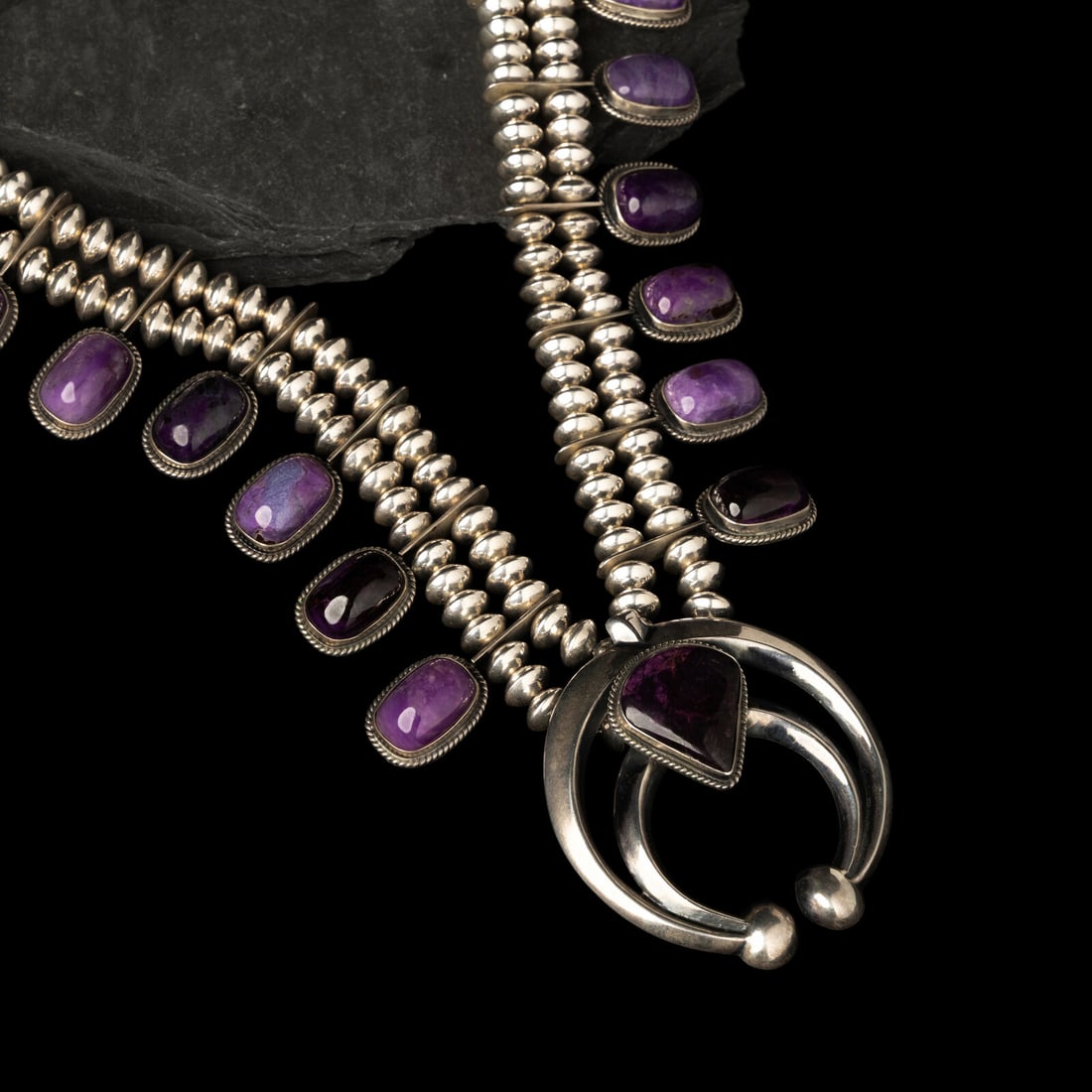 Carol and Wilson Begay (DinÈ, act. since 1969) Sterling Silver and Sugilite Squash Blossom: Carol and Wilson Begay (DinÈ, act. since 1969) Sterling Silver and Sugilite Squash Blossom Necklace signed WB with artist's hat hallmark length 20-1/2 inches naja length 2-5/8 inches x width 2-3/