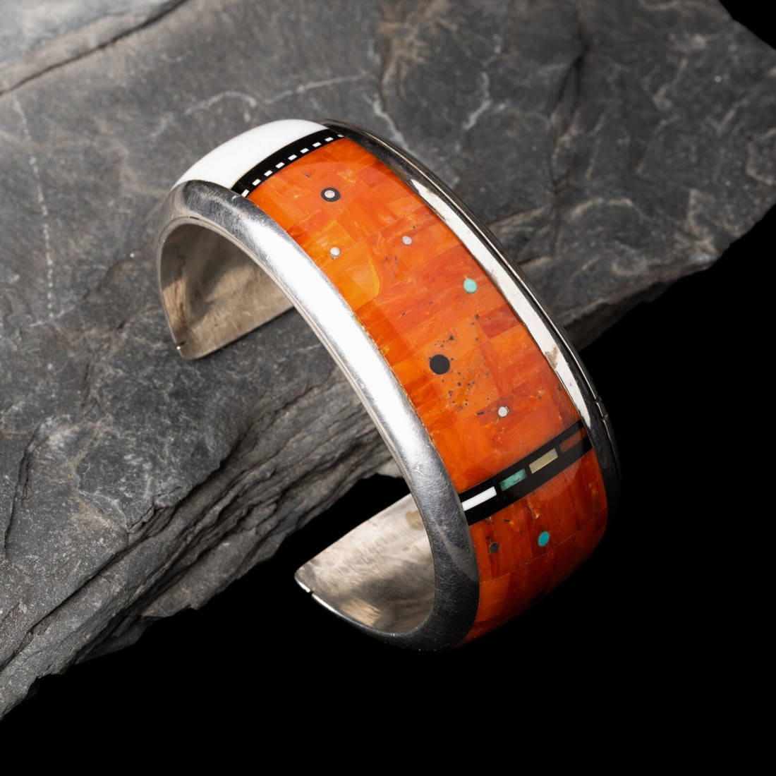 Jesse Monongya (DinÈ, 1952-2024) Silver and Mosaic Inlay Cuff Bracelet: Jesse Monongya (DinÈ, 1952-2024) Silver and Mosaic Inlay Cuff Bracelet tapered shank set with coral, onyx, turquoise, and shell; signed on reverse JMONONGYE width 1-1/2 inches tapers to 1 inch in