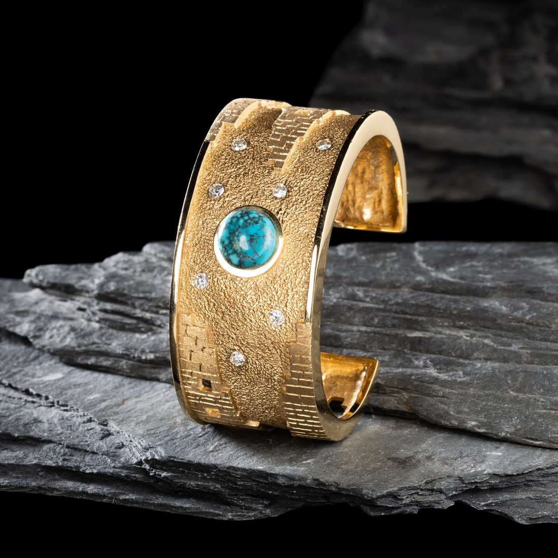 Don Supplee (Hopi, b. 1965) 14K Gold, Turquoise, and Diamond Pueblo Cuff Bracelet: Don Supplee (Hopi, b. 1965) 14K Gold, Turquoise, and Diamond Pueblo Cuff Bracelet featuring towering pueblos with window cutouts along the shank and set with a central turquoise cabochon and seven dia