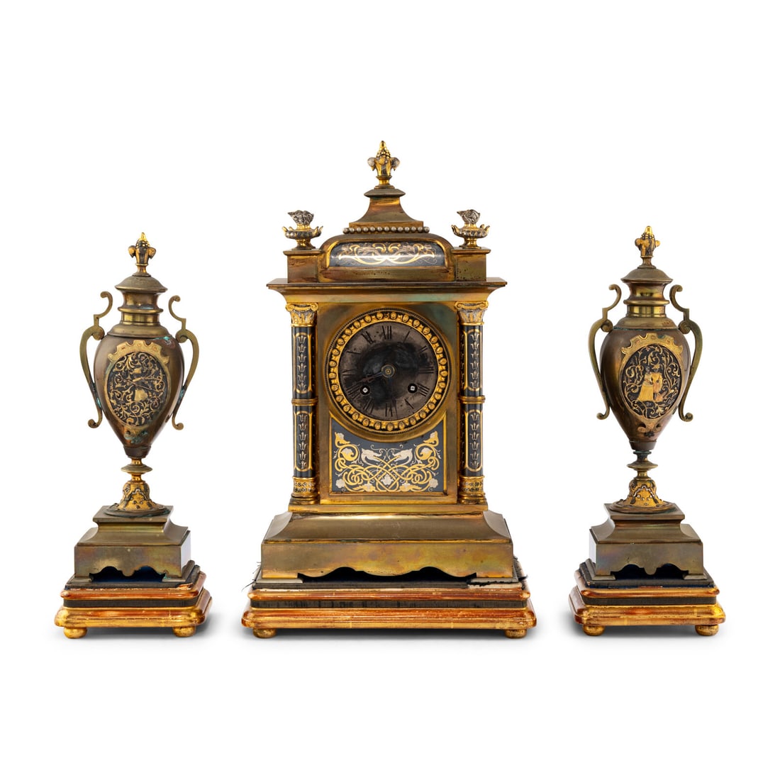 A French Brass and Mixed Metals Clock Garniture: A French Brass and Mixed Metals Clock Garniture Movement by Japy FrËres, Late 19th Century comprising a clock and a pair of urns, each set on a giltwood stand. Height overall of clock 15 inches.
