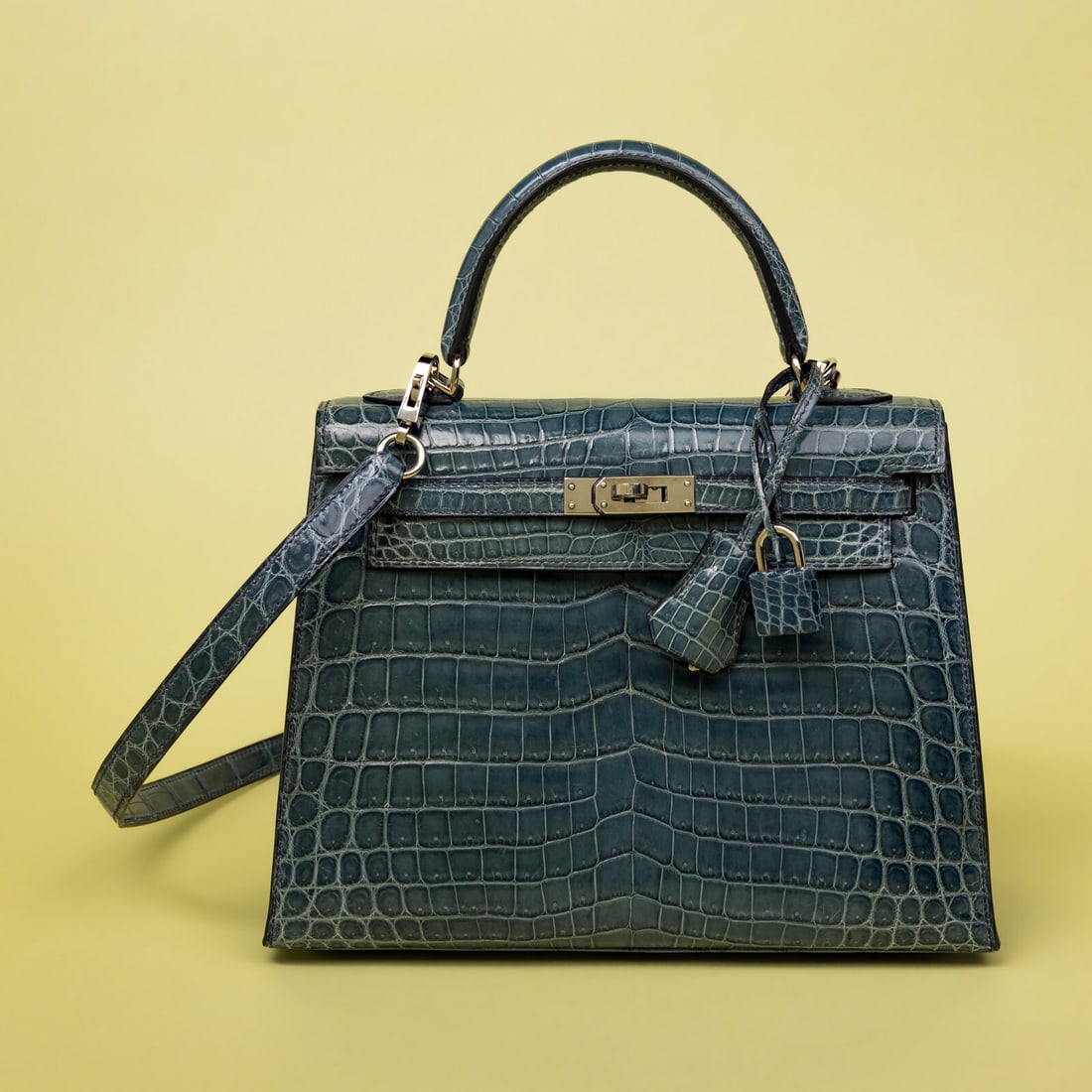 Hermès, Kelly 25 in Bleu Colvert Crocodile with Strap: Hermès, Kelly 25 in Bleu Colvert Crocodile with Strap Kelly 25 Sellier in Bleu Colvert shiny niloticus crocodile skin with palladium-plated hardware. Rolled handle and removable flat shoulder strap. 