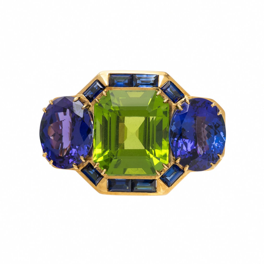 Peridot, Tanzanite, and Yellow Gold Brooch: Peridot, Tanzanite, and Yellow Gold Brooch Emerald cut peridot weighing approximately 22.30 carats by formula, and oval and baguette cut tanzanite. Yellow gold. 1 3/8 x 7/8 inches. Gross weight: 14.60