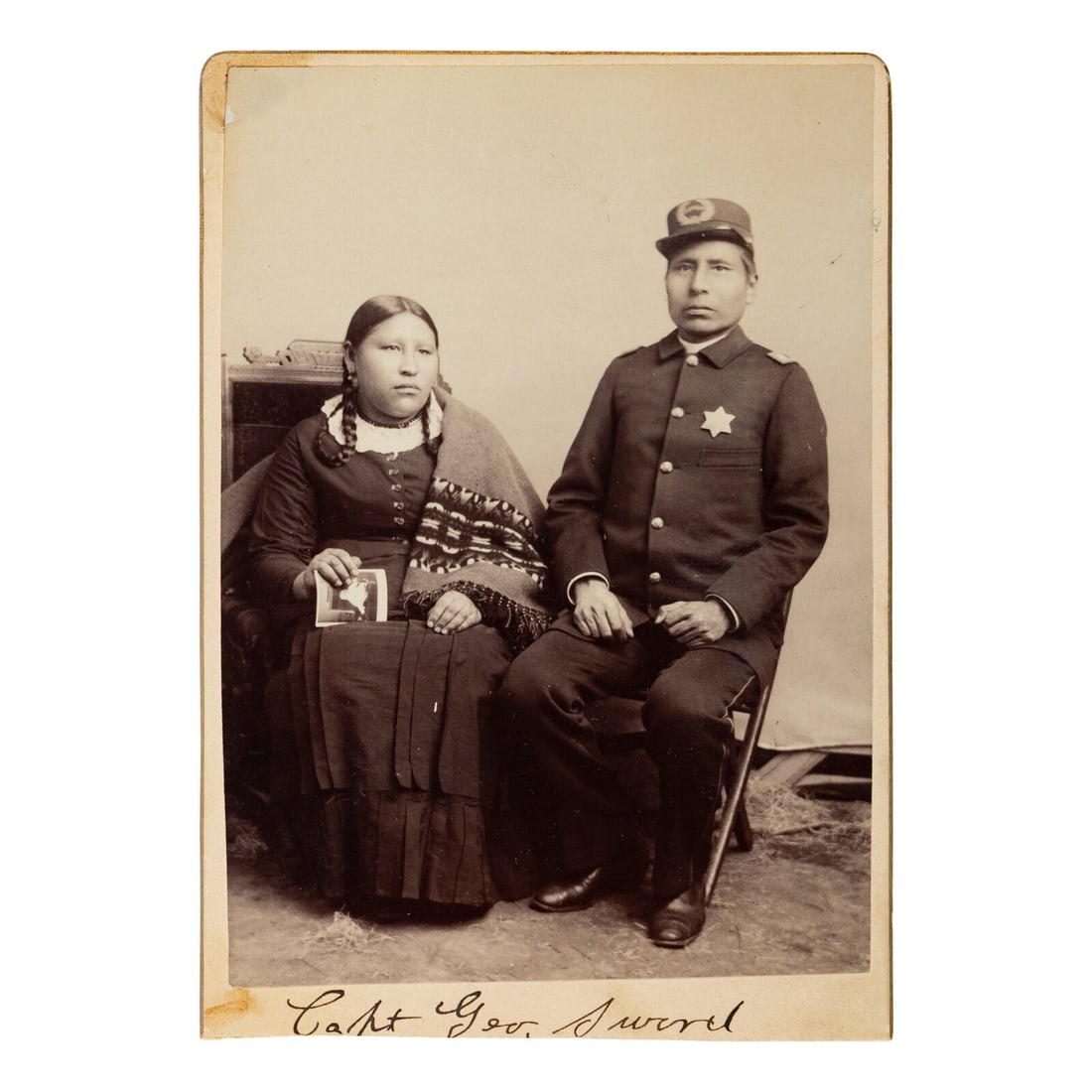[Native Americana]. Cabinet card of Pine Ridge Tribal Police Captain George Sword and wife.: [Native Americana]. Cabinet card of Pine Ridge Tribal Police Captain George Sword and wife. Cabinet photograph of George Sword, Captain of Pine Ridge Tribal Police, and wife, verso with imprint of J. 