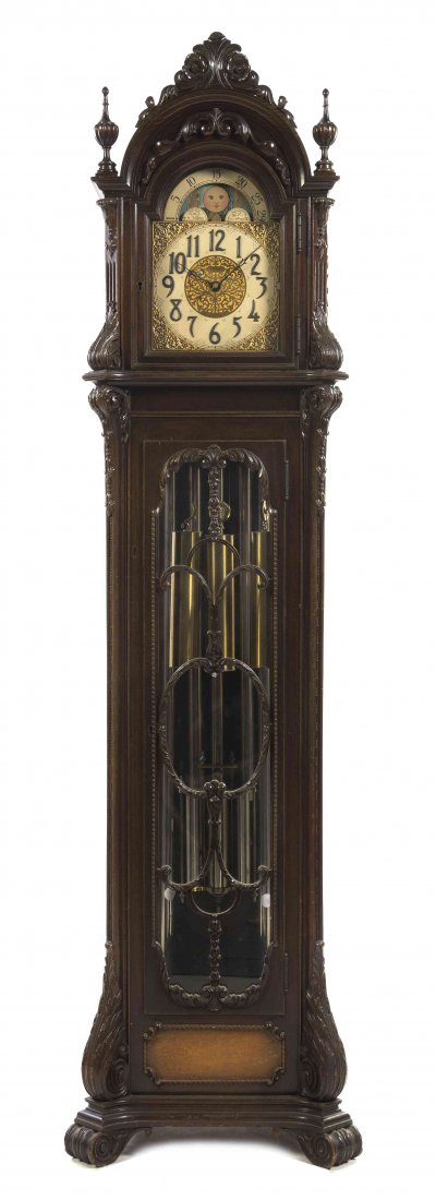 An American Mahogany Tall Case Clock, Telechron, Height: An American Mahogany Tall Case Clock, Telechron, having a peaked carved cornice flanked by two urn form finials above the arched glazed door revealing a circular enameled moon phase dial with Roman ho