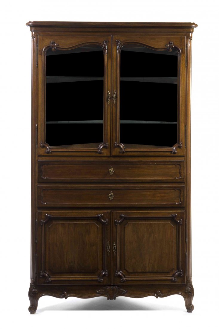 A Louis XV Style Corner Cabinet, Paul Sormani, Height: A Louis XV Style Corner Cabinet, Paul Sormani, having a stepped pediment over two glazed doors opening to two shelves, above two long drawers and two paneled doors, with a shaped skirt raised on short
