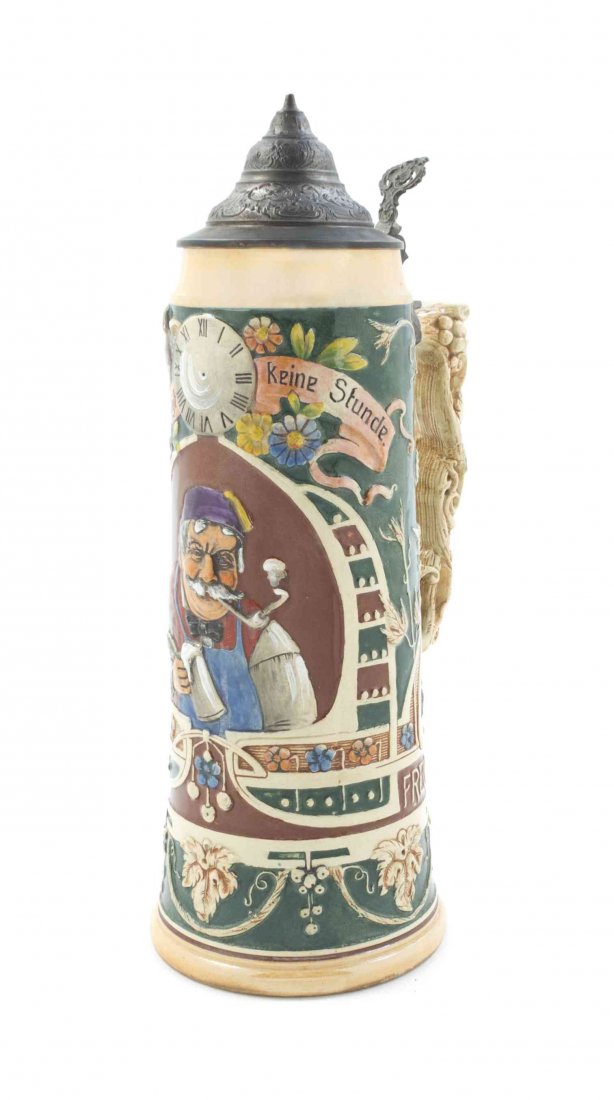 A German Pewter Mounted Ceramic Stein, Height 13: A German Pewter Mounted Ceramic Stein, of tapering cylindrical form, with a grapevine form handle, decorated with a man smoking a pipe and drinking from a stein beneath a clock dial, base impressed 96