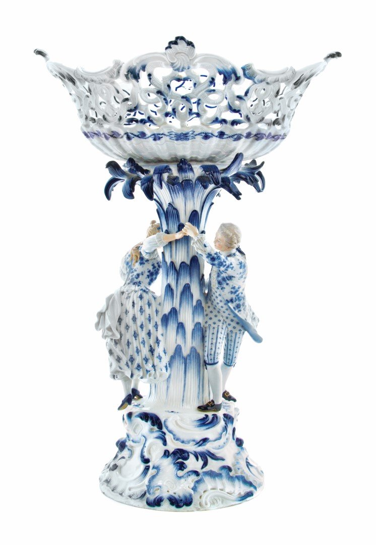 A Meissen Porcelain Figural Compote, Height 19 1/2: A Meissen Porcelain Figural Compote, having a pierced basket with Blue Onion decoration, raised on a tree trunk form standard with a gentleman and a lady in chase, having crossed swords mark in underg
