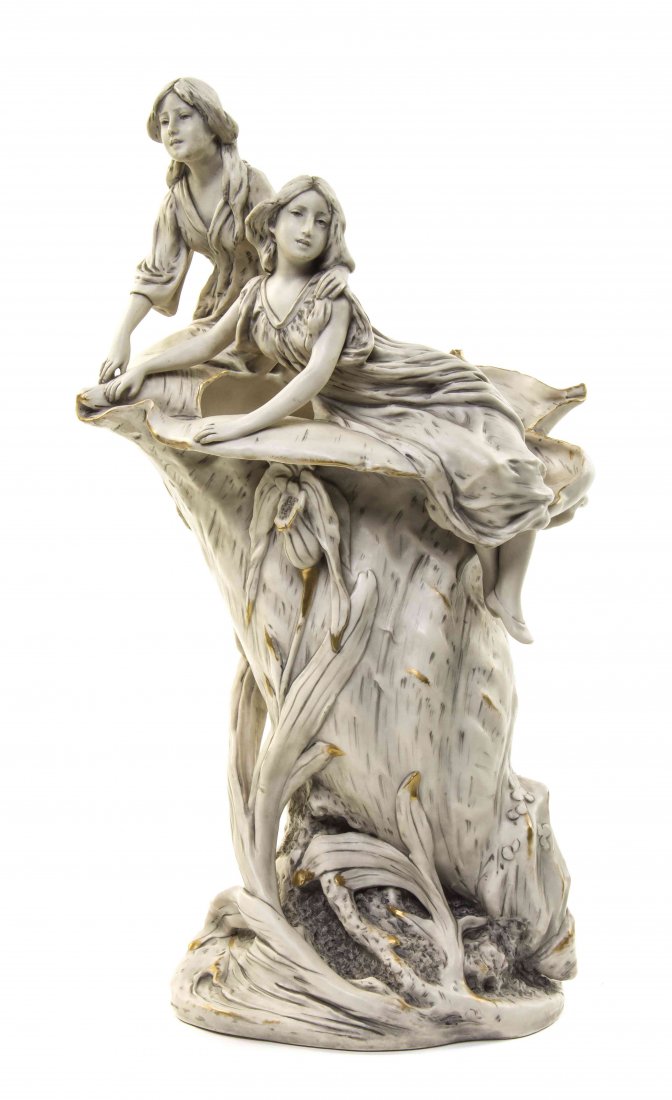 A Royal Dux Art Nouveau Porcelain Figural Vase, Height: A Royal Dux Art Nouveau Porcelain Figural Vase, depicting two maidens sitting on the edge of a seashell, with further applied foliate decoration, initialed HS and dated 1904, the base further impresse