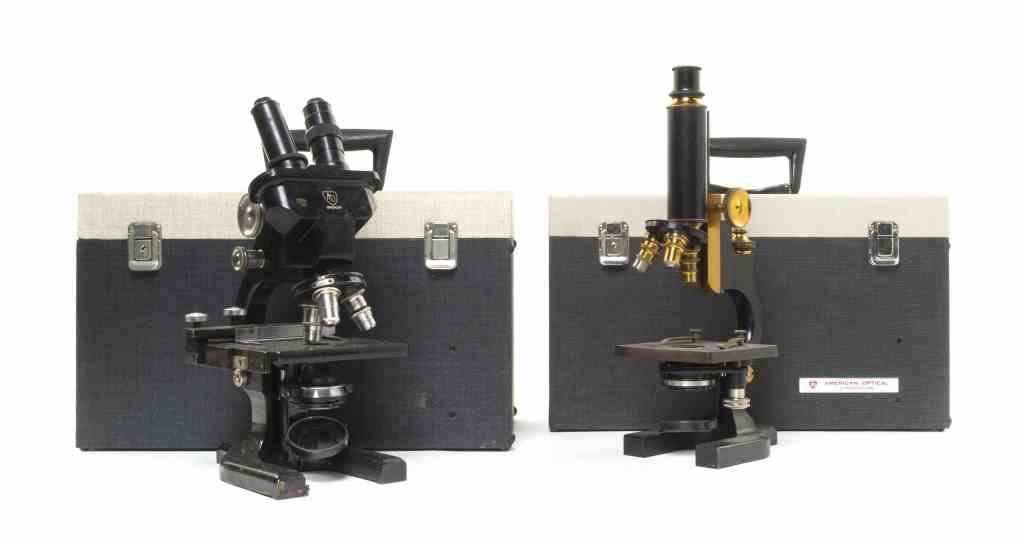 Two American Enameled Steel Microscopes, Spencer,: Two American Enameled Steel Microscopes, Spencer, Buffalo, New York, pre-1924 serial number 24784 and a binocular head example, each with a fitted case. Height of taller 14 3/4 inches (extended). Prop