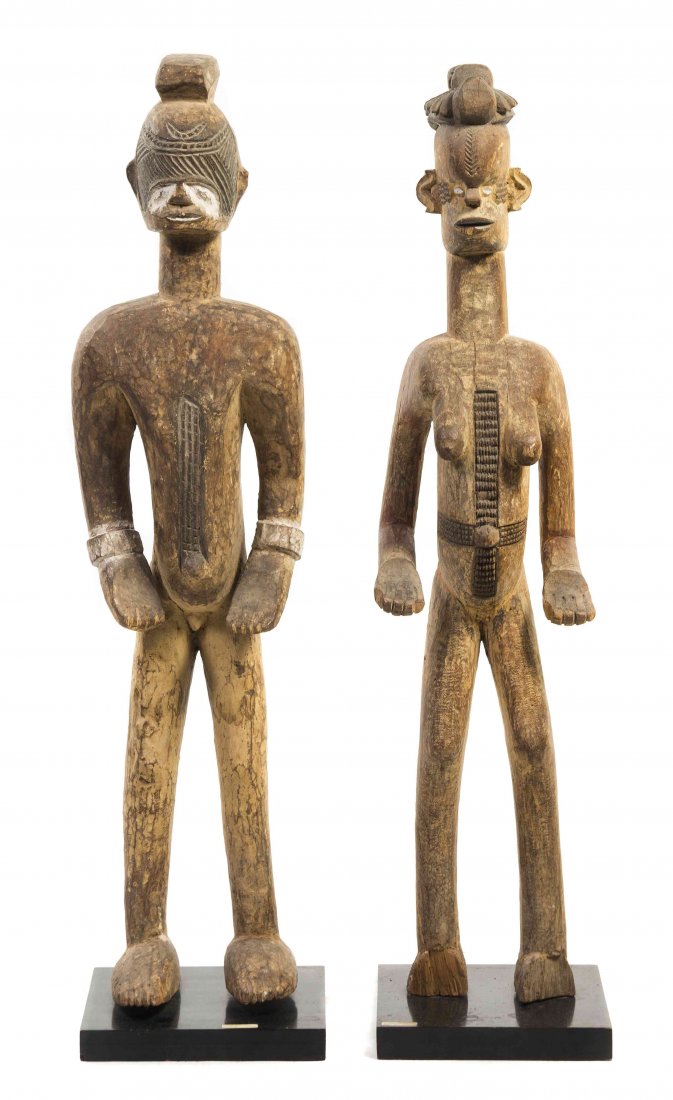 Two African Carved Wood Figures, Ibo Tribe, Height of: Two African Carved Wood Figures, Ibo Tribe, depicting a standing male and female, each with stylized features and scarification. Height of taller 47 inches. Property from the Estate of Jeanne Marienth