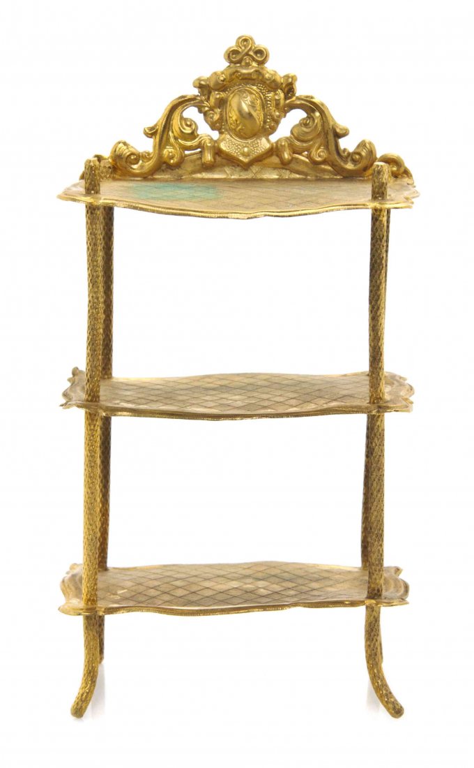 An Ormolu Etagere, Erhard & Sohne, Height 5 1/8 x width: An Ormolu Etagere, Erhard & Sohne, having a pierced foliate and shield decorated back crest over three shaped rectangular shelves, raised on splayed legs. Height 5 1/8 x width 2 3/4 x depth 2 inches.