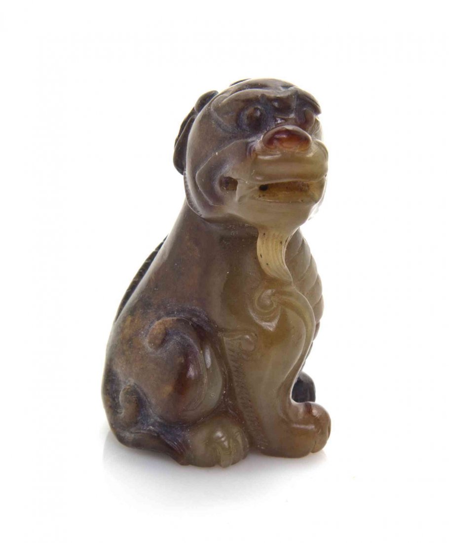 A Chinese Carved Jade Toggle of a Qilin, Height 1 5/8: A Chinese Carved Jade Toggle of a Qilin, of pale celadon stone with russet skin, the beast depicted seated with scrolled horn and bifurcated tail. Height 1 5/8 inches. The Adell Venus Collection of Mi
