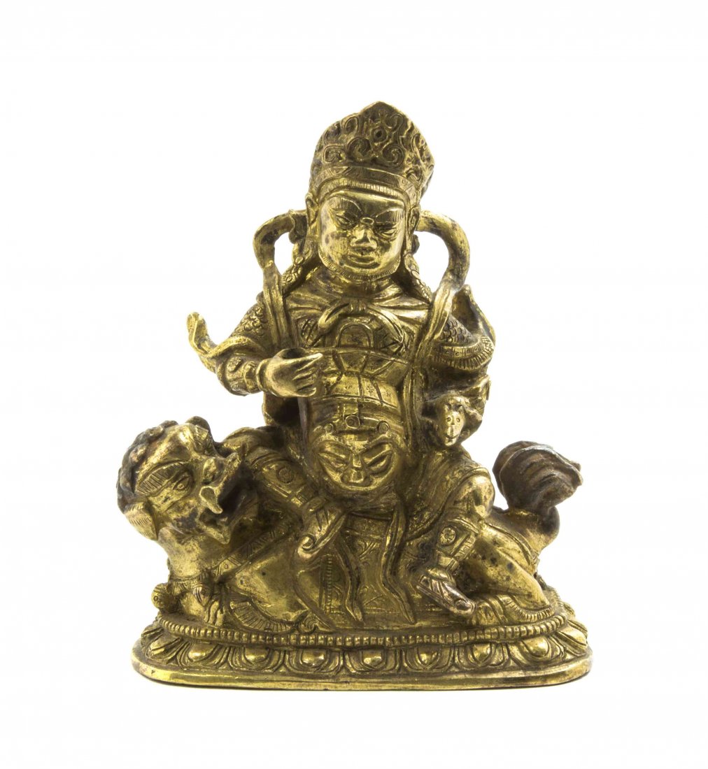 A Tibetan Gilt Bronze Figure of a Deity, Height 4 1/8: A Tibetan Gilt Bronze Figure of a Deity, depicted with a peaked crown and seated upon a lion, raised on a lotus form base. Height 4 1/8 inches.