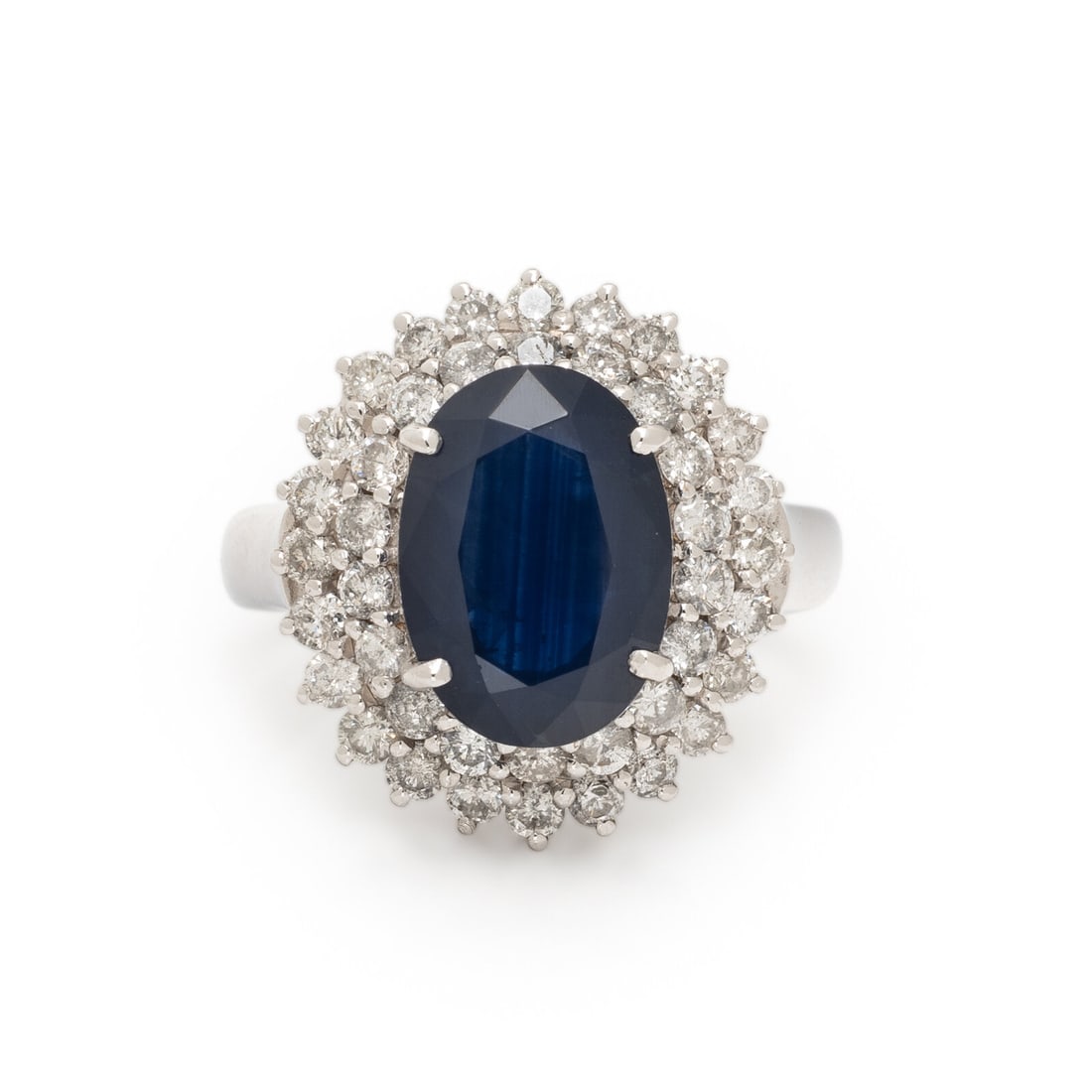 Sapphire, Diamond, and White Gold Ring: Sapphire, Diamond, and White Gold Ring Featuring an oval sapphire weighing approximately 3.50 - 4.00 carats by formula, surrounded by round brilliant cut diamonds weighing approximately 1.40 carats to