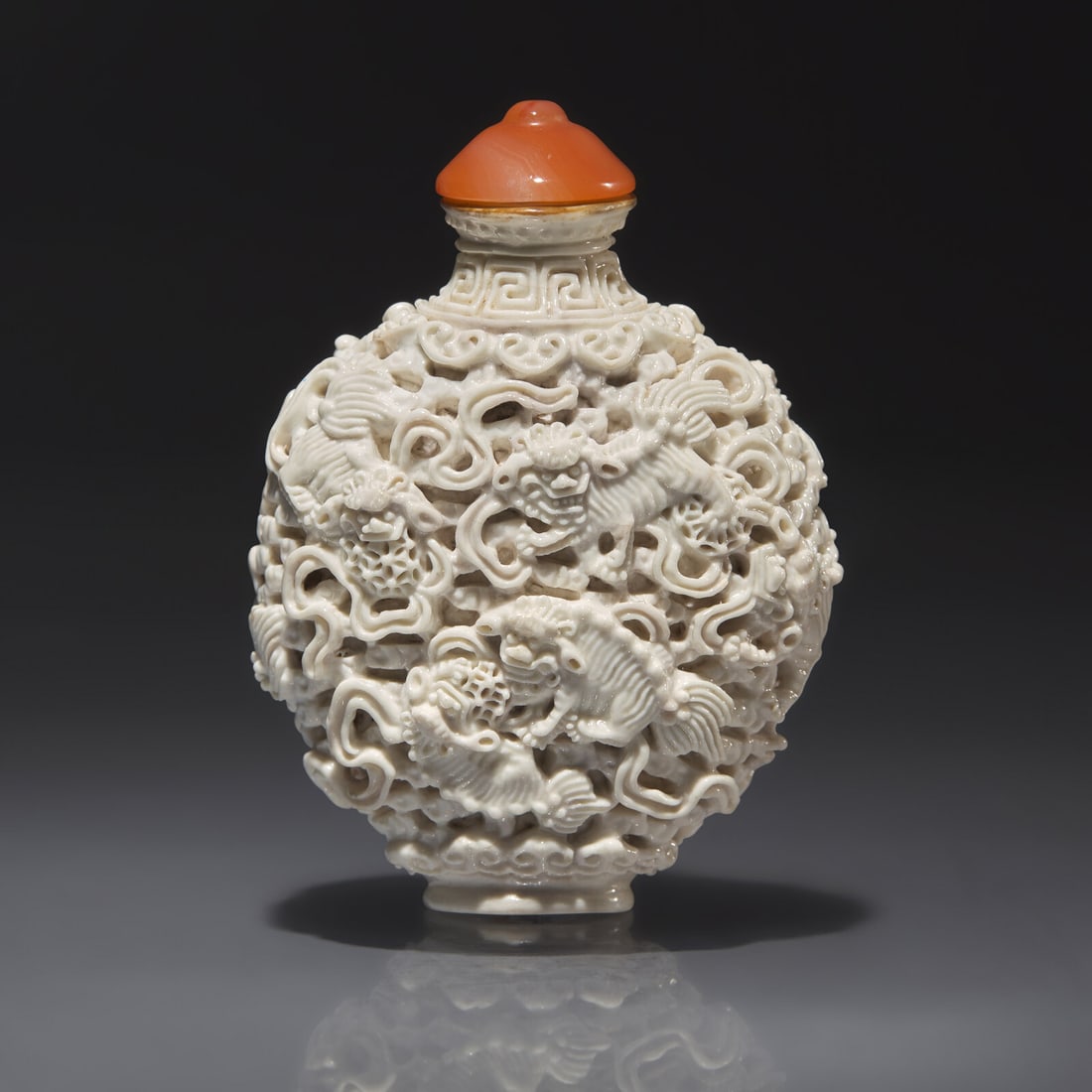 A Chinese Molded White-Glazed Porcelain "Buddhist Lions" Snuff Bottle, Qing Dynasty, Jiaqing Mark: A Chinese Molded White-Glazed Porcelain "Buddhist Lions" Snuff Bottle, Qing Dynasty, Jiaqing Mark and of the Period 清嘉慶 白釉模印鏤雕獅