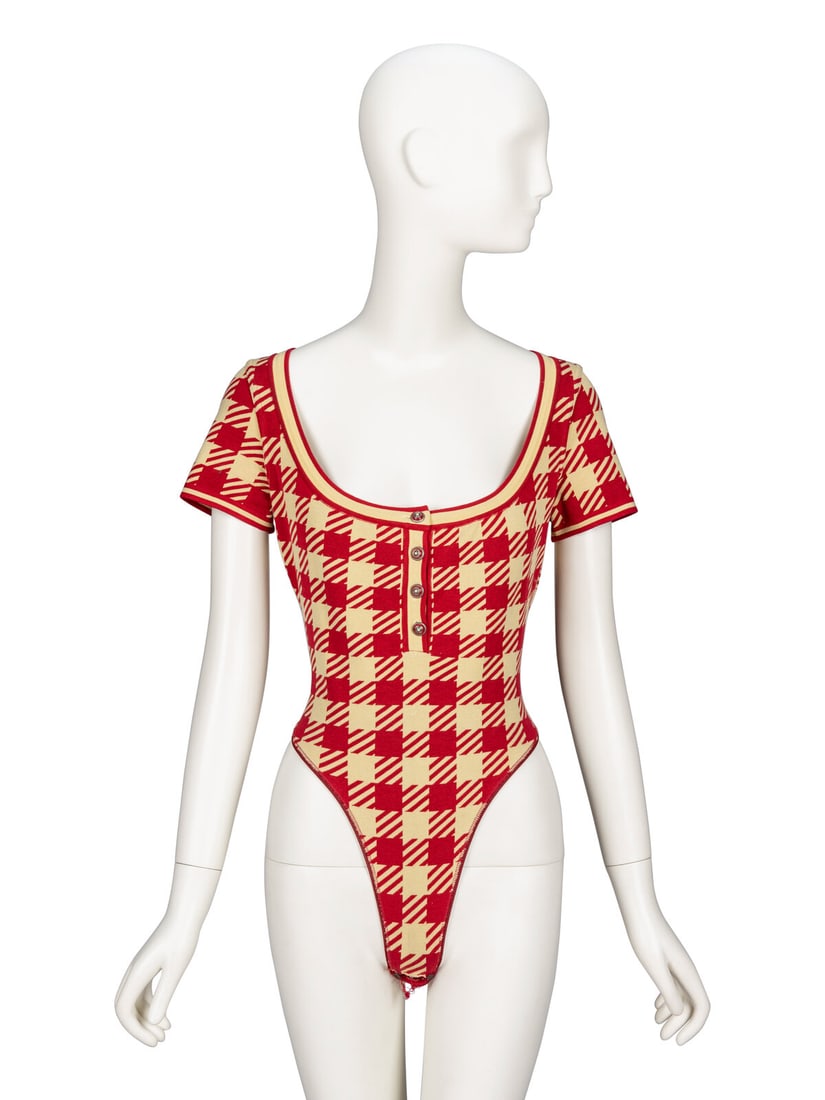 Ala‘a, Red Gingham Knit Bodysuit, S/S 1991: AlaÔa, Red Gingham Knit Bodysuit, S/S 1991 Bodysuit in crimson & beige gingham-print stretch knit. Round scoop neckline with four button closures at front. Short cap sleeves. French-cut leg