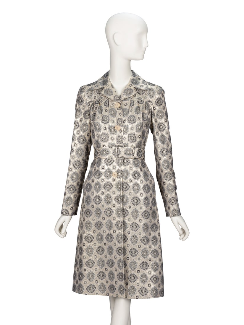 Prada, Brocade Coatdress: Prada, Brocade Coatdress Belted coatdress in a metallic gold silk-blend brocade. Wide spread collar with notched mini lapels. Full-length sleeves with button closures at cuffs. Lightly gathered,