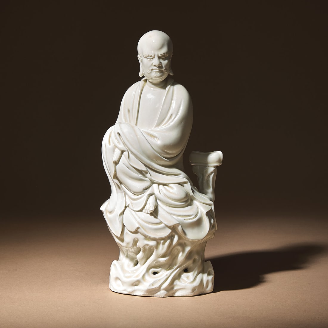A Chinese Blanc-de-Chine Porcelain Seated Figure of Damo with 'He Chaozong' Mark, Qing Dynasty: A Chinese Blanc-de-Chine Porcelain Seated Figure of Damo with 'He Chaozong' Mark, Qing Dynasty 清 何朝宗款“隻履西歸”德化&#