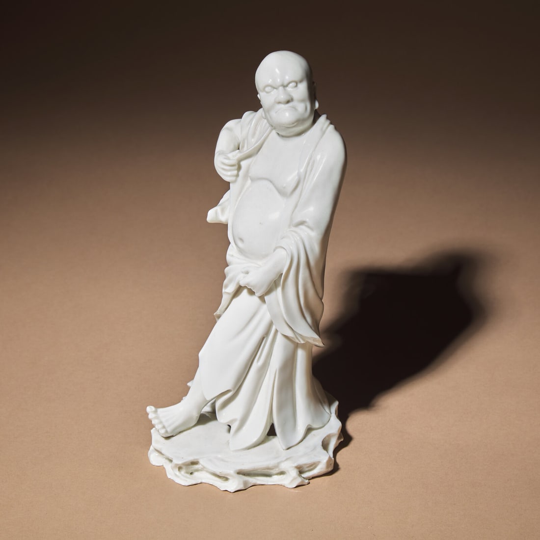 A Chinese Blanc-de-Chine Porcelain Standing Figure of a Luohan, Qing Dynasty: A Chinese Blanc-de-Chine Porcelain Standing Figure of a Luohan, Qing Dynasty 清 德化白瓷羅漢立像 Qing Dynasty (1644-1911) The figure standing on a