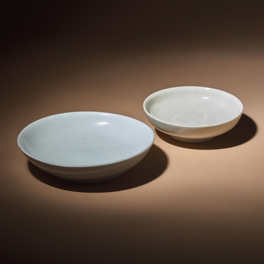 Two Chinese Blanc-de-Chine Porcelain Shallow Bowls, Ming Dynasty: Two Chinese Blanc-de-Chine Porcelain Shallow Bowls, Ming Dynasty 明 德化白瓷圈足盤兩件 Ming Dynasty (1368-1644) The larger dish features a w