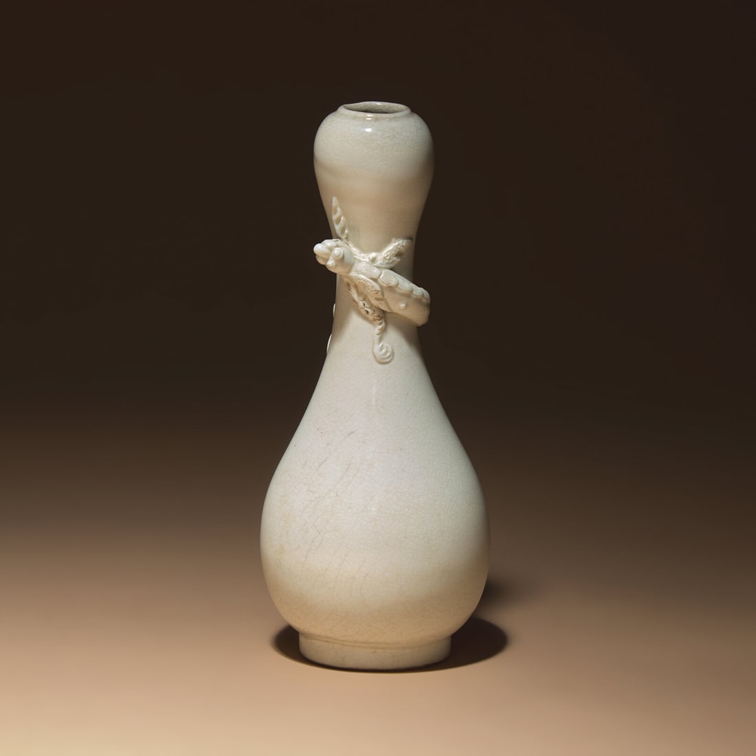 A Chinese White Glazed Porcelain 'Chilong' Bottle Vase, Qing Dynasty: A Chinese White Glazed Porcelain 'Chilong' Bottle Vase, Qing Dynasty 清 白釉盤螭龍瓶 Qing Dynasty (1644-1911) The bottle features a garlic-shaped mouth and is