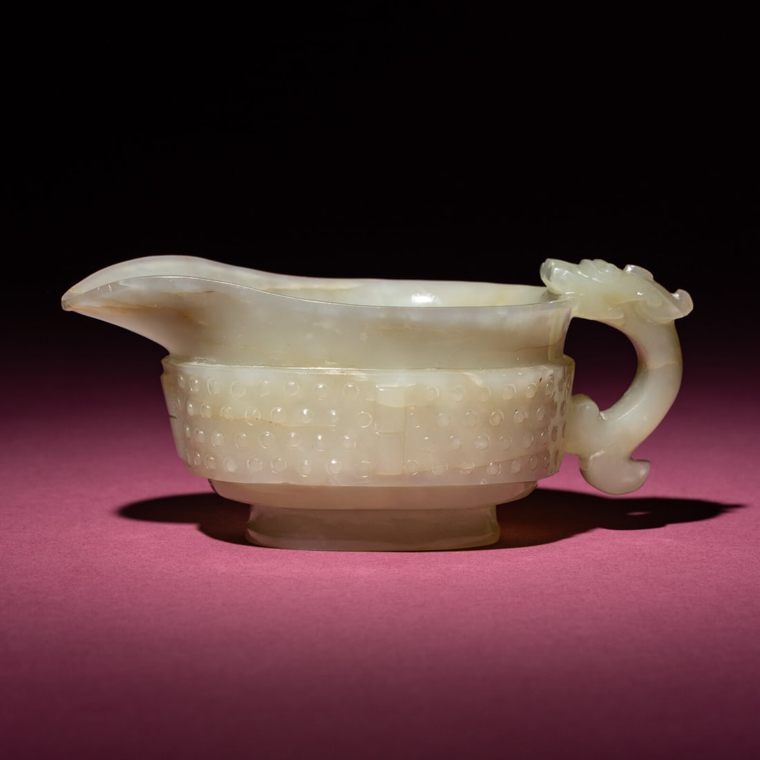 A Chinese Pale Celadon Jade Archaistic Yi Vessel, 17th Century: A Chinese Pale Celadon Jade Archaistic Yi Vessel, 17th Century 清早期 青白玉仿古龍紋匜 17th Century The rounded body of oval section s