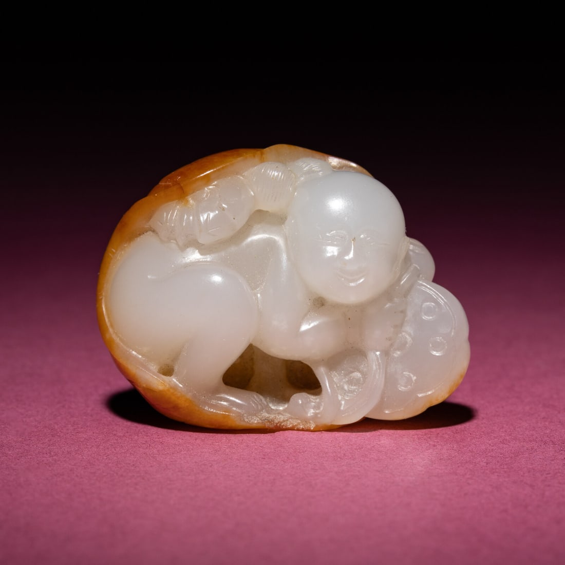 A Chinese Russet and White Jade Carving of a Boy with Lotus Pad, 18th/19th Century: A Chinese Russet and White Jade Carving of a Boy with Lotus Pad, 18th/19th Century 清中期 白玉留皮童子持荷把件 18th/19th C