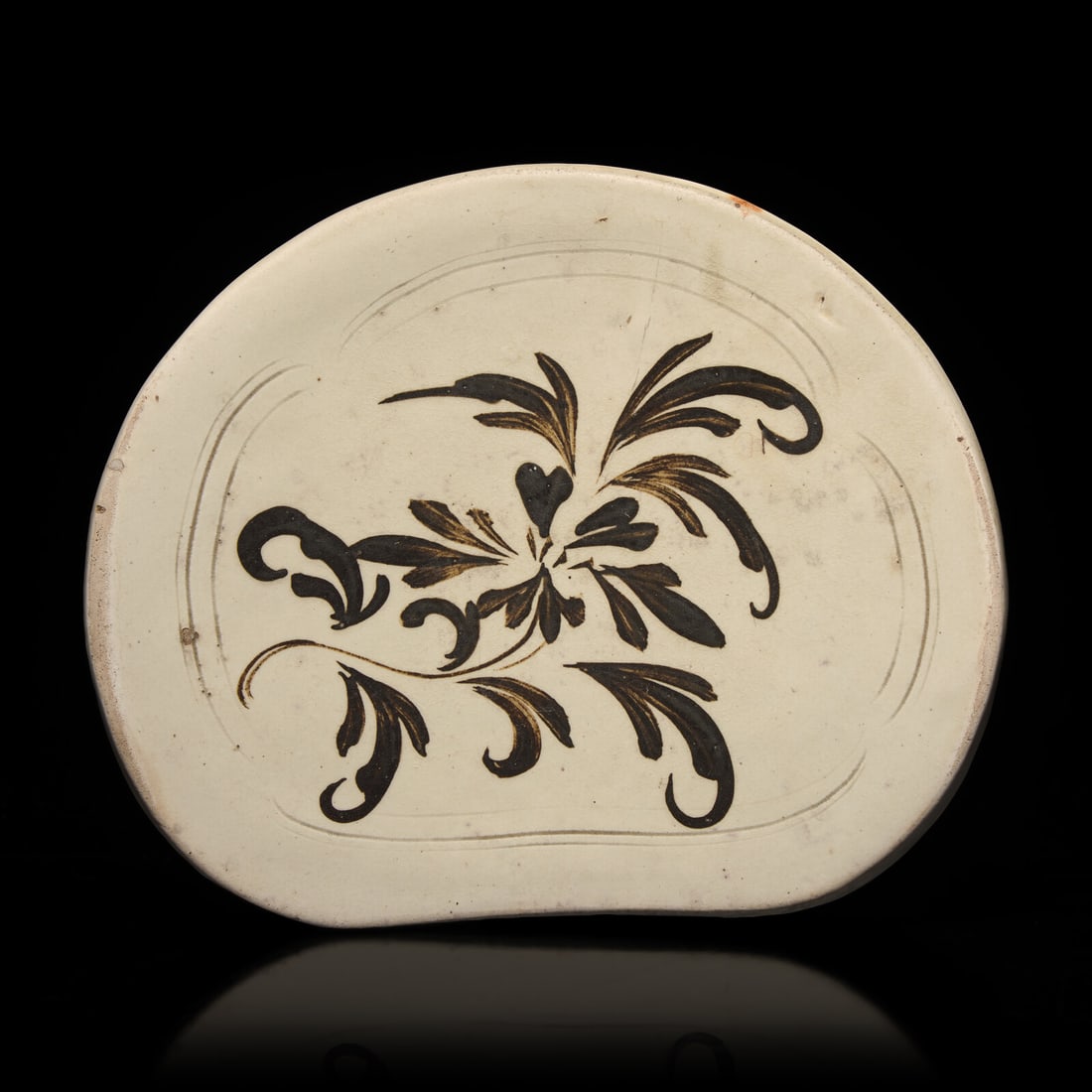 A Chinese Cizhou Slip-Decorated Pillow, Song Dynasty: A Chinese Cizhou Slip-Decorated Pillow, Song Dynasty 宋 磁州窯萱草紋枕 Song Dynasty (960-1279) Of curved and sloped reniform, the top freely painted wit