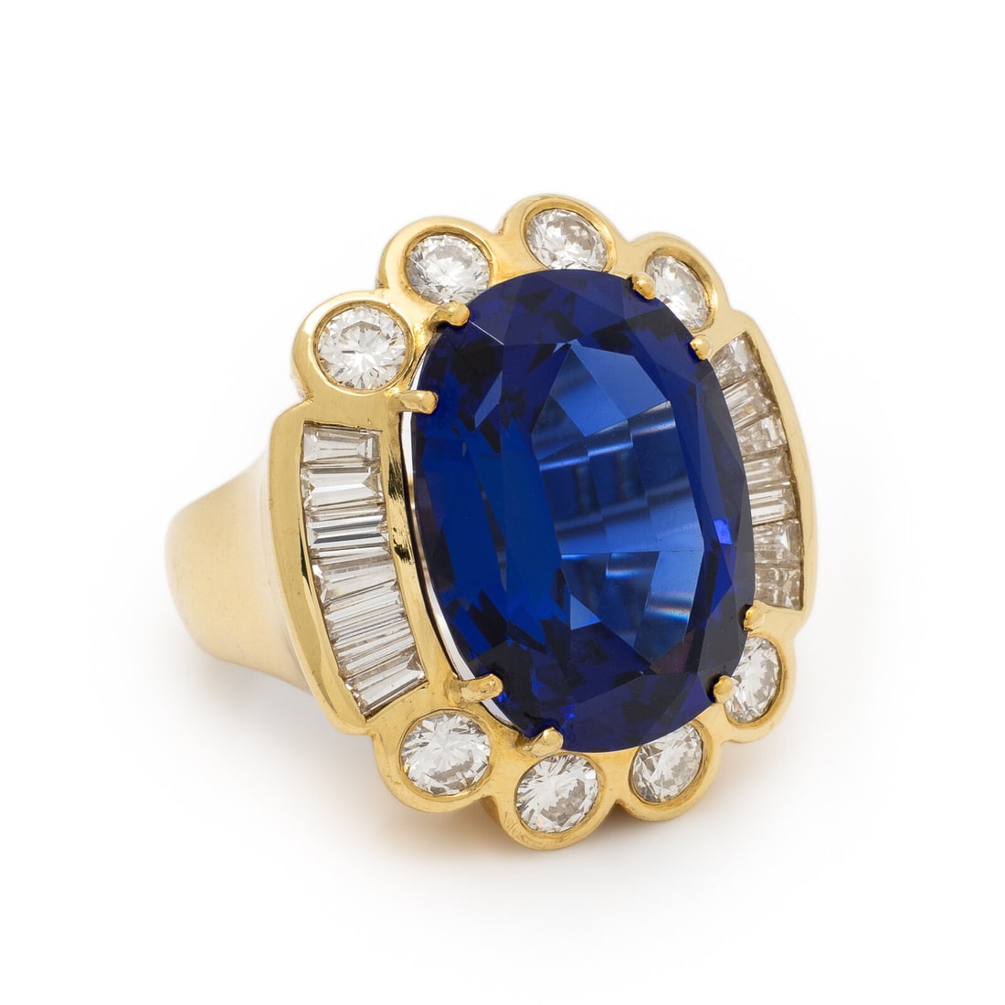 Tanzanite, Diamond, and Yellow Gold Ring: Tanzanite, Diamond, and Yellow Gold Ring Featuring an oval tanzanite weighing approximately 24.40 carats by formula, framed by round brilliant and tapered baguette cut diamonds weighing approximately 