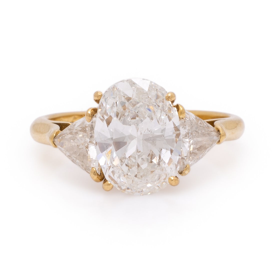 Diamond and Yellow Gold Ring: Diamond and Yellow Gold Ring Featuring an oval brilliant cut diamond weighing 2.07 carats, flanked by trillion cut diamonds weighing approximately 0.95 carat total. Mounted in 18 karat yellow gold. Ri