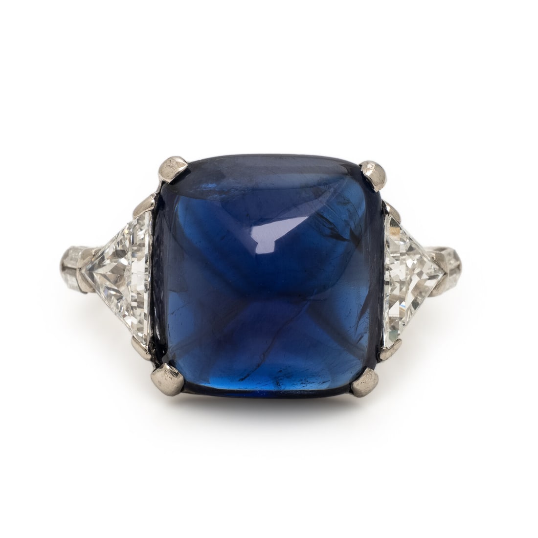 Sapphire, Diamond, and Platinum Ring: Sapphire, Diamond, and Platinum Ring Featuring a sugarloaf cabochon sapphire weighing approximately 10.28 carats, flanked by trillion and baguette cut diamonds weighing approximately 1.35 carats total