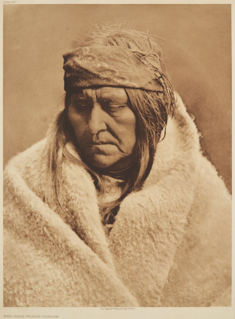 Edward Curtis (American, 1868-1952) Two Bear Woman - Piegan, 1911: Edward Curtis (American, 1868-1952) Two Bear Woman - Piegan, 1911 plate 190 on Japanese Gampi tissue mounted to larger sheet, in mat. 18 x 13-1/4 inches (457 x 336 mm) This lot is located in