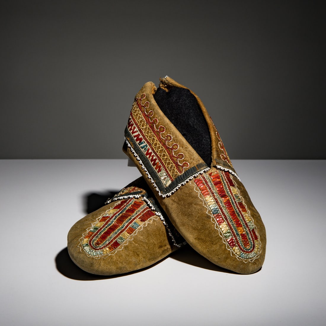 Seneca Quilled Hide Moccasins: Seneca Quilled Hide Moccasins second quarter 19th century thread-sewn, softly tanned hide; plaited quillwork on vamps in colors of red, blue, yellow, and one-thread one-quill sewing on cuffs; cuffs