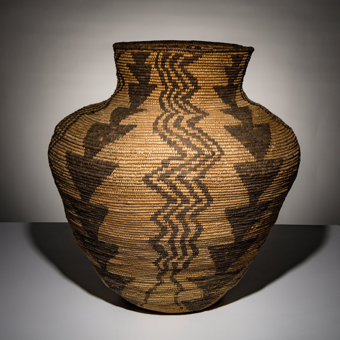 Apache Basketry Olla: Apache Basketry Olla ca 1900 alternating designs of zigzagging and stacked triangles height 23-3/4 inches x diameter 23 inches This lot is located in Chicago. Provenance: Ex David Cook Fine Art