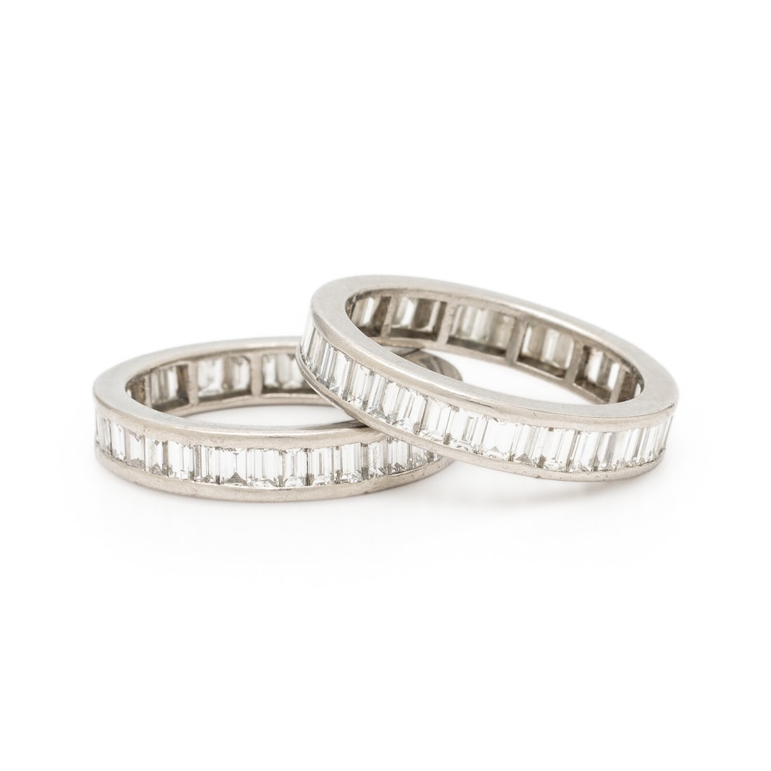 Two Platinum and Diamond Eternity Bands: Two Platinum and Diamond Eternity Bands Each set with baguette cut diamonds weighing approximately 1.15 carats total. Platinum. Both ring size 5 1/4. Gross weight: 4.45 dwt. Property of a Lady from No
